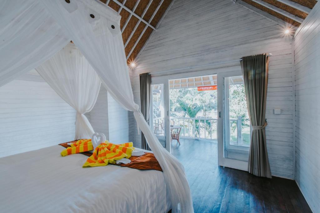 una camera con un letto bianco a baldacchino di Paluh Beach Huts a Nusa Lembongan