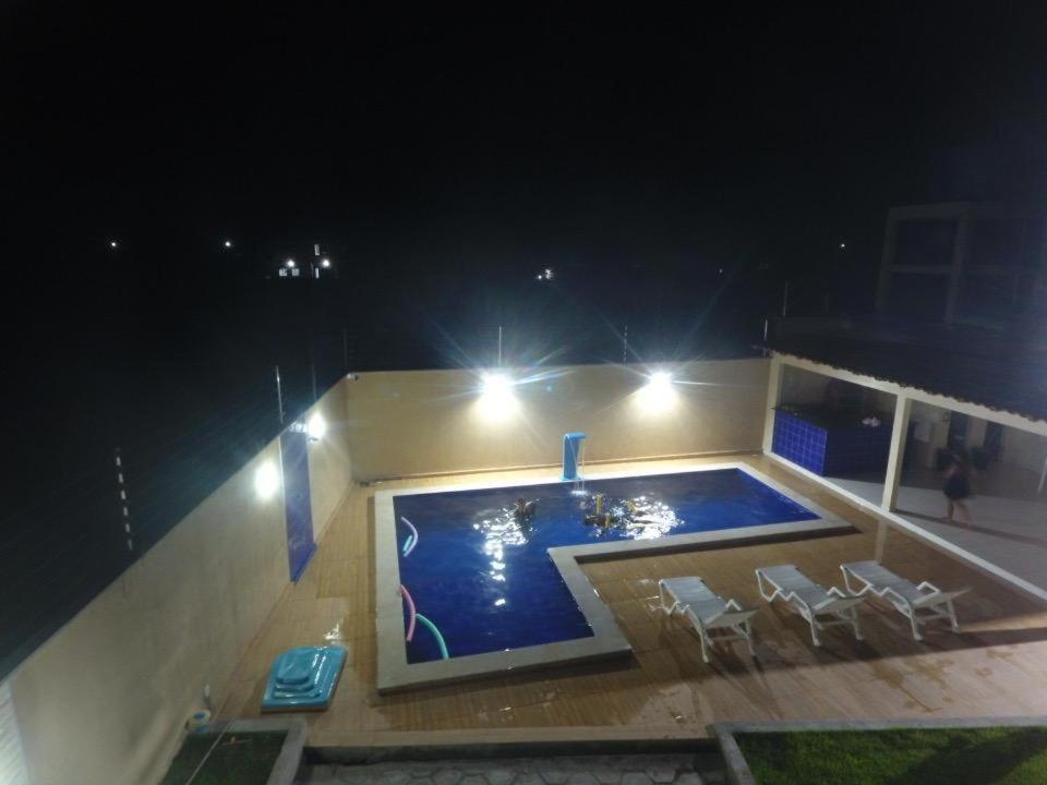 una piscina por la noche con sillas y luces en Dunas Residence - Casa 11, en Santo Amaro