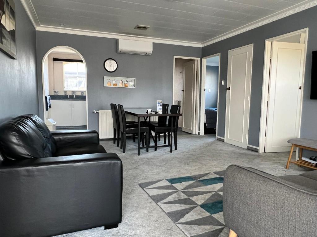 a living room with a couch and a table with chairs at ASURE Surrey Court Motel Invercargill in Invercargill