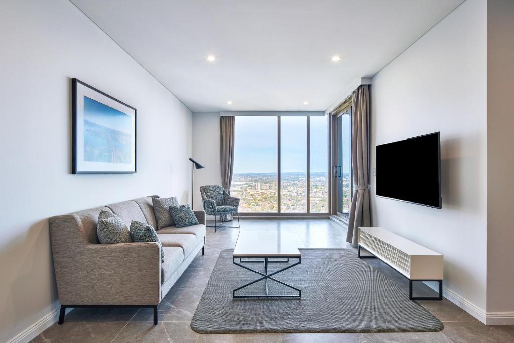 a living room with a couch and a tv at Meriton Suites George Street, Parramatta in Sydney