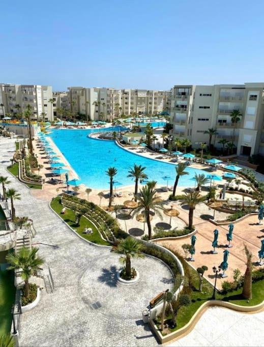 une grande piscine avec des palmiers et des bâtiments dans l'établissement Appartement Résidence Palm Lake Monastir, à Monastir