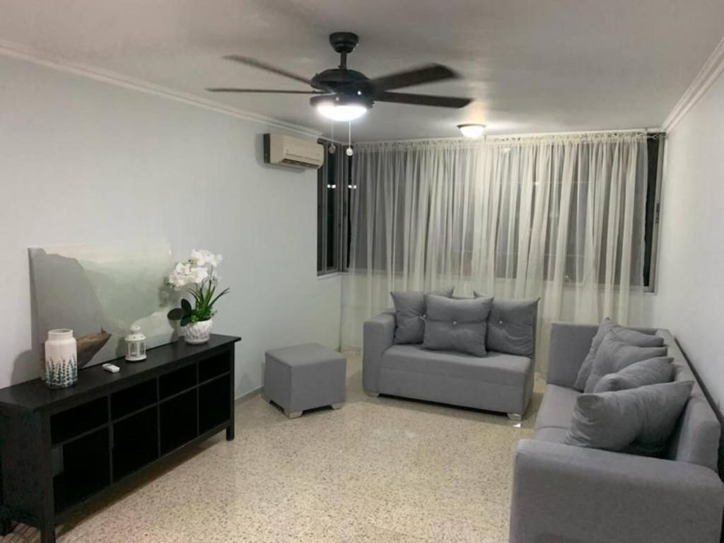 ein Wohnzimmer mit 2 Sofas und einem Deckenventilator in der Unterkunft Apartamento bien equipado en el centro de la ciudad in Santo Domingo