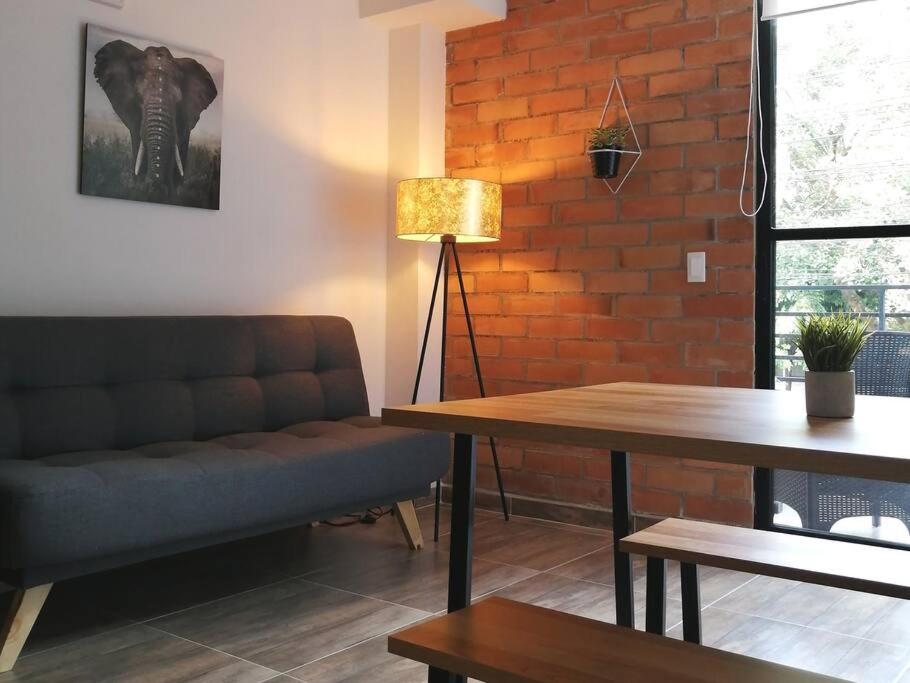 un soggiorno con divano e muro di mattoni di Apartamento en Medellín-clínica las Americas a Medellín