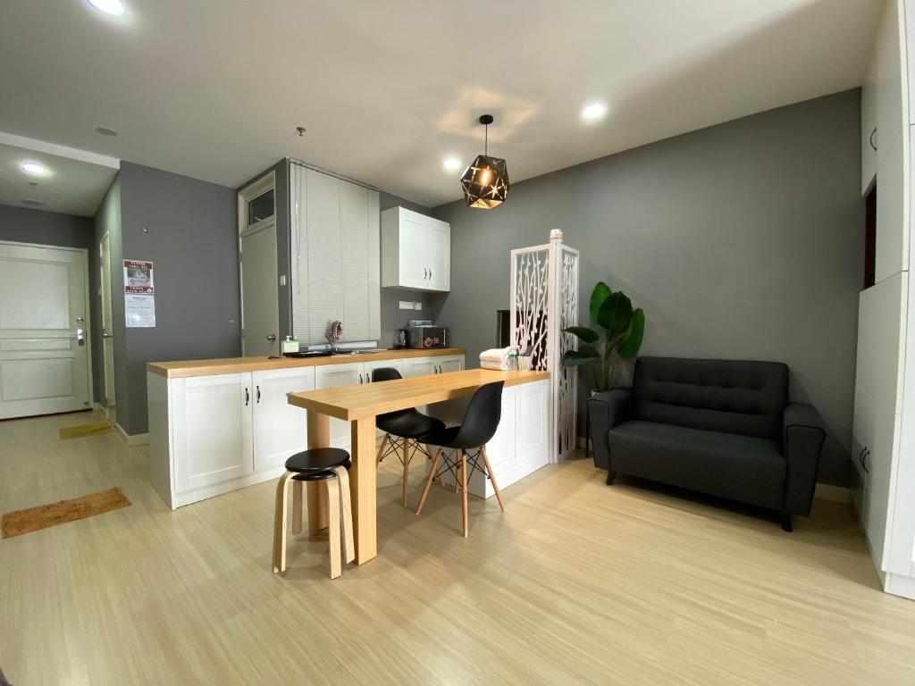 a kitchen with a wooden table and a black couch at A Modern & Homely Studio with Pool and Gym in Kampar