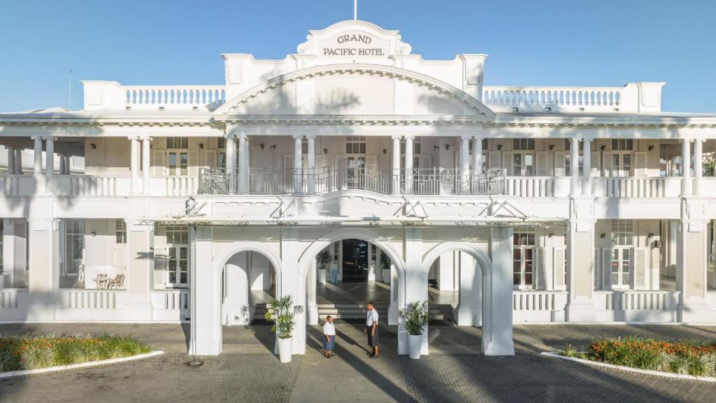 duas pessoas em frente a um edifício branco em Grand Pacific Hotel em Suva