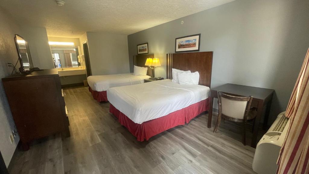 a hotel room with two beds and a mirror at Days Inn & Suites by Wyndham Winnie in Winnie
