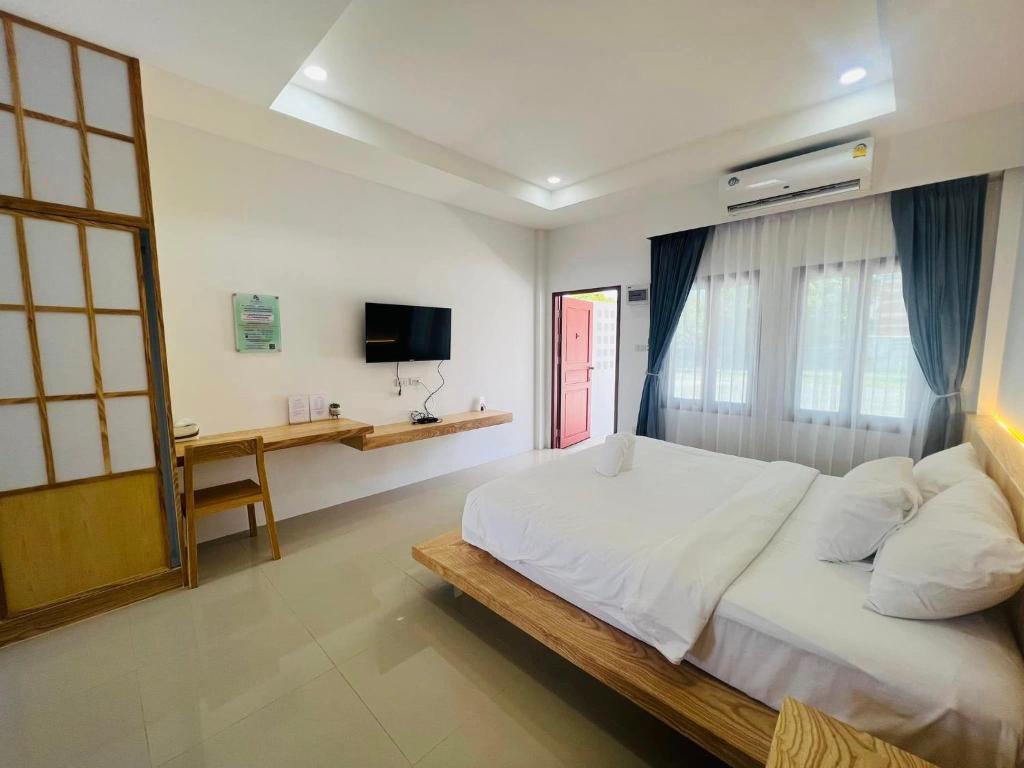 Schlafzimmer mit einem großen weißen Bett und einem Schreibtisch in der Unterkunft สราญรัตน์รีสอร์ท in Ban Noen Makok
