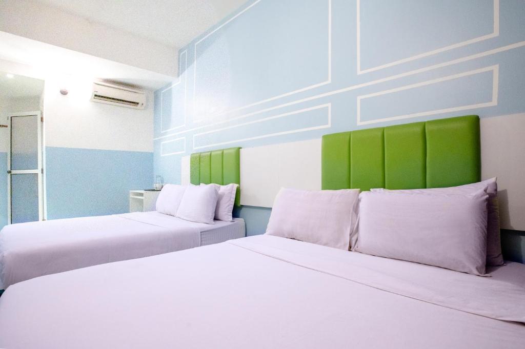 two beds in a room with green and white at The Quay Hotel Bukit Bintang in Kuala Lumpur