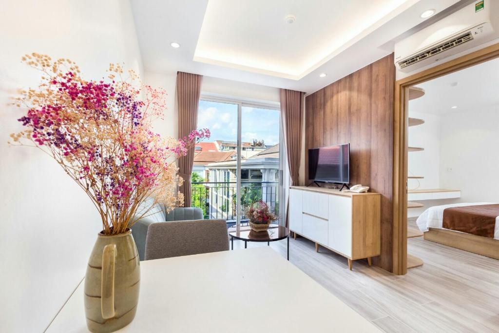 a living room with a vase with flowers in it at SEA APARTHOTEL in Ho Chi Minh City