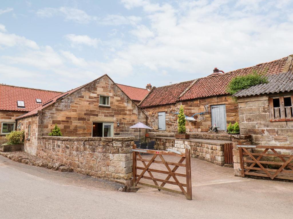 an old stone house with a fence and a gate at Mulgrave Cottage in Staithes