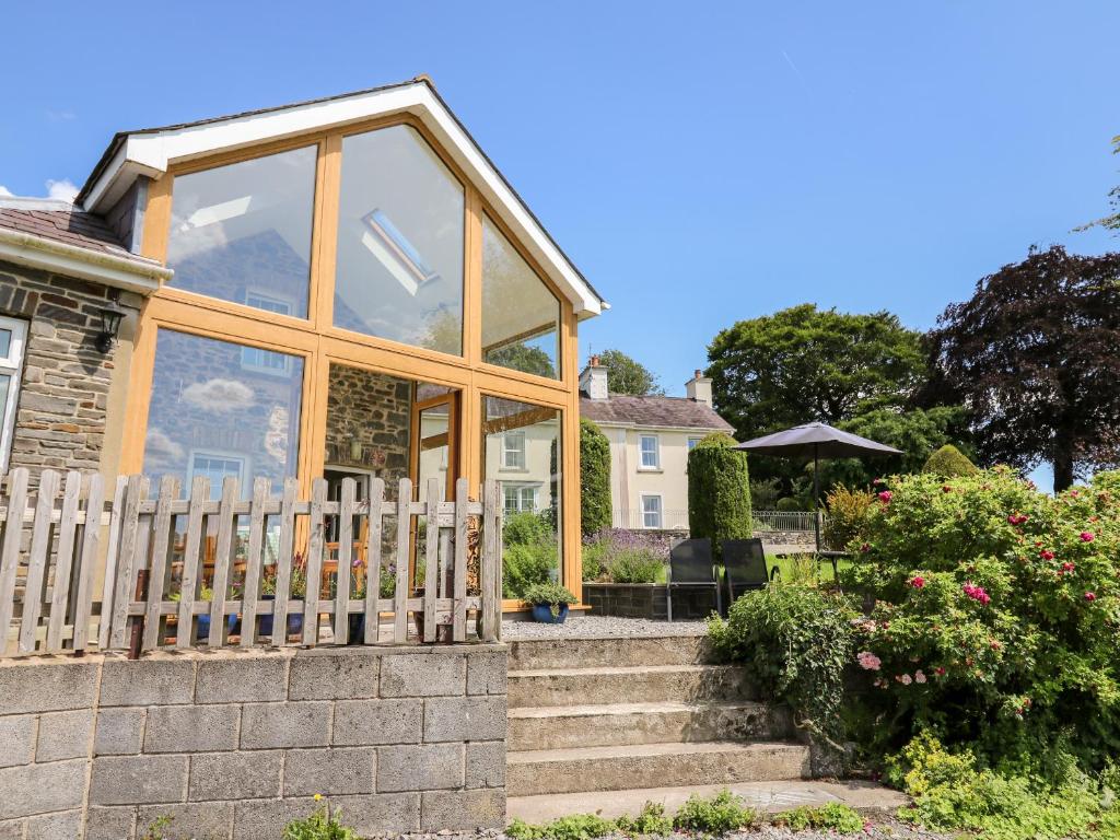 a house with a conservatory with stairs and a fence at Llety'r Wennol in Llanycrwys
