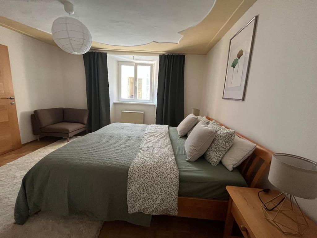 a bedroom with a bed and a chair and a window at Franziskaner Suites #9 in Graz
