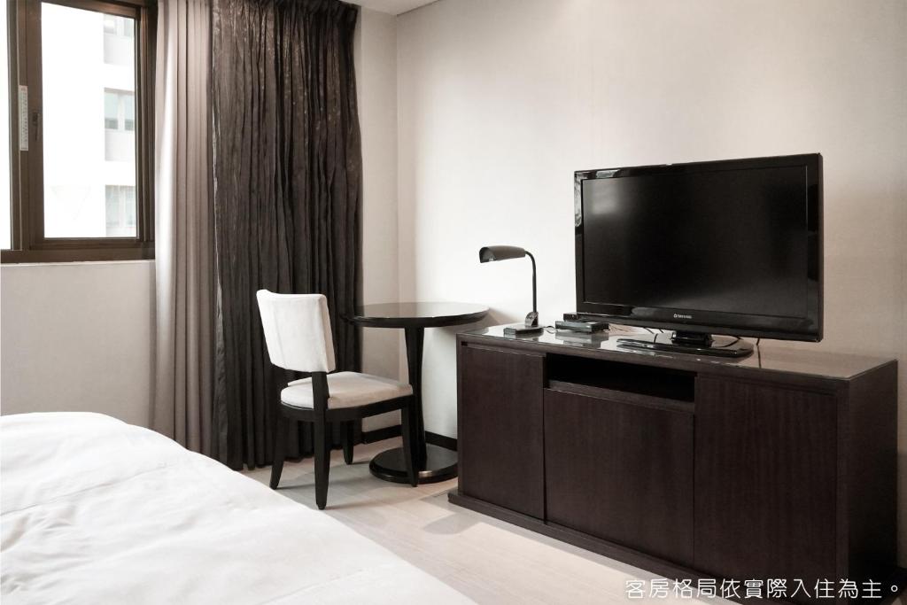 a hotel room with a television and a table and chair at Talmud Hotel Kaohsiung LoveRiver in Kaohsiung