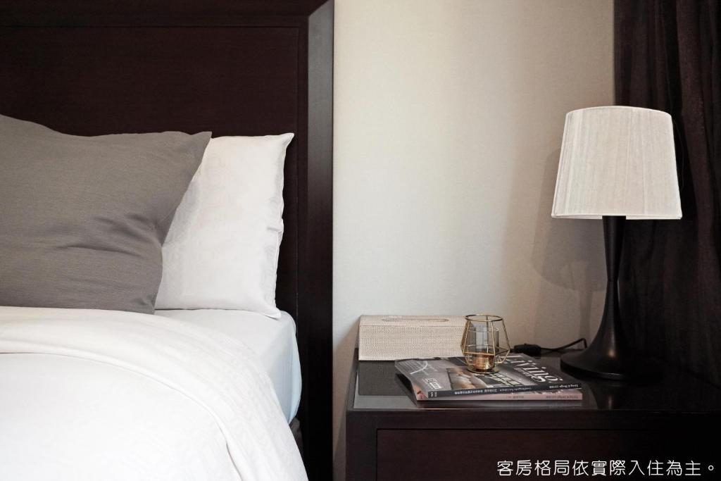 a bed with a lamp on a nightstand next to a bed at Talmud Hotel Kaohsiung LoveRiver in Kaohsiung
