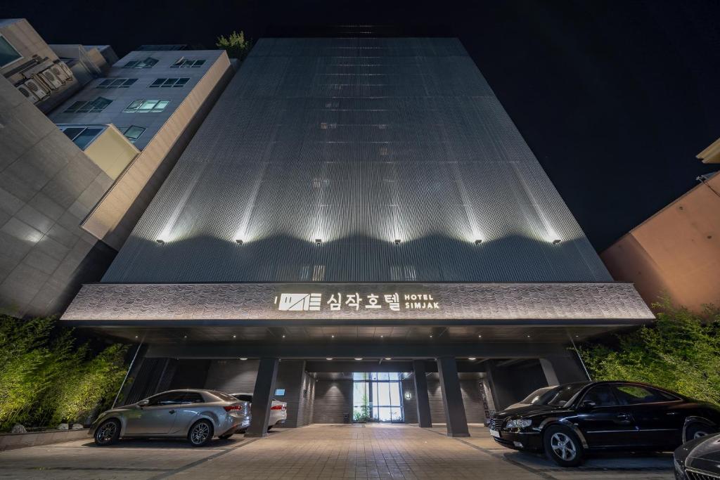 a building with two cars parked in front of it at Simjak Hotel Dongtan By Aank in Hwaseong