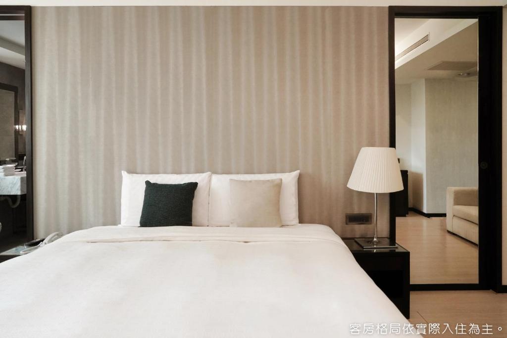 a bedroom with a large white bed and a lamp at Talmud Hotel Kaohsiung LoveRiver in Kaohsiung