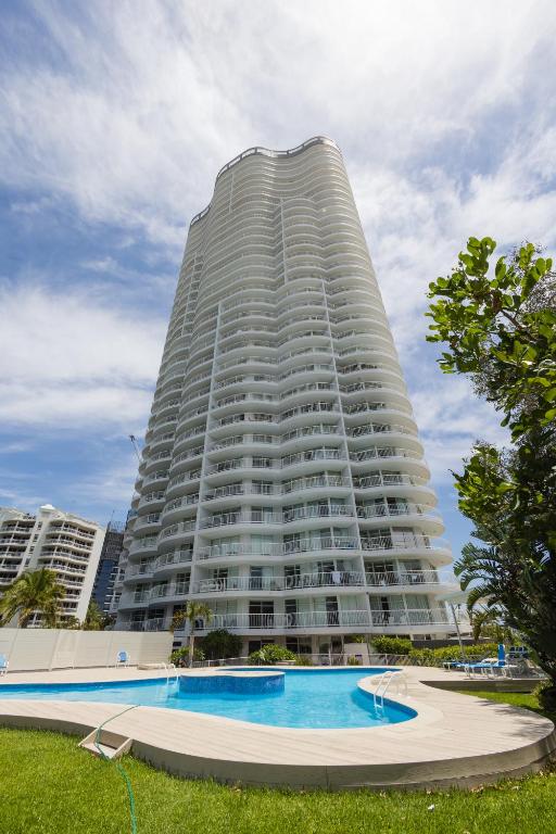 a large building with a swimming pool in front of it at Burleigh Surf Apartments in Gold Coast
