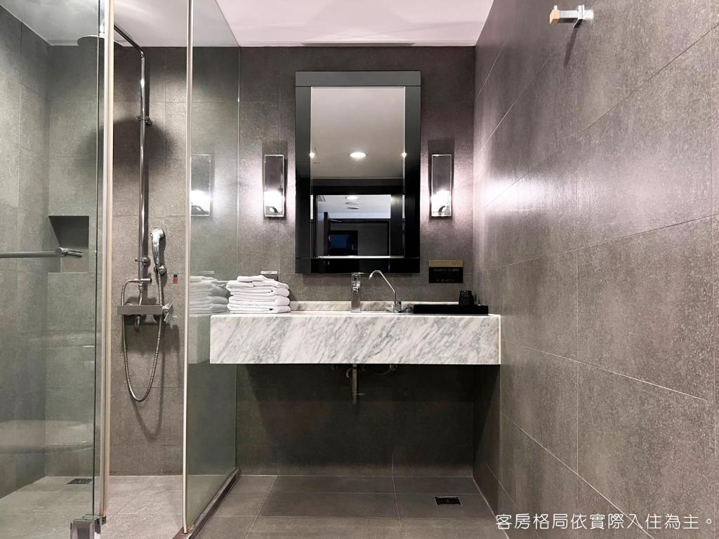 a bathroom with a sink and a shower with a mirror at Talmud Hotel Kaohsiung LoveRiver in Kaohsiung