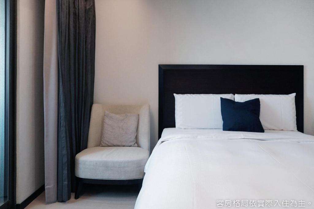 a bedroom with a bed and a chair at Talmud Hotel Kaohsiung LoveRiver in Kaohsiung