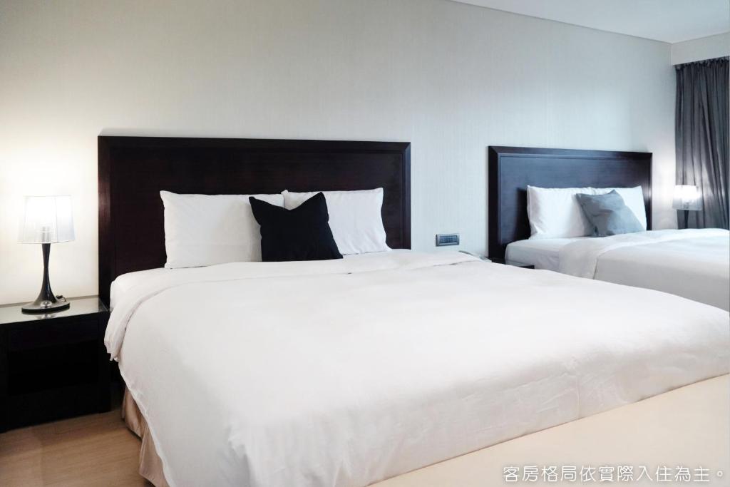 two beds in a hotel room with white and black at Talmud Hotel Kaohsiung LoveRiver in Kaohsiung