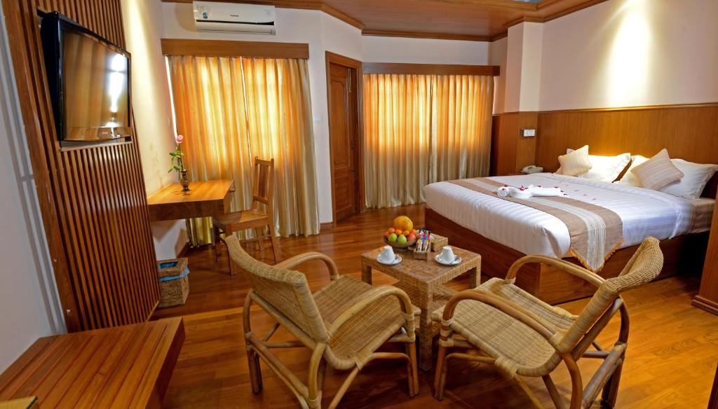 een hotelkamer met een bed en een tafel en stoelen bij Hotel Sidney in Yangon