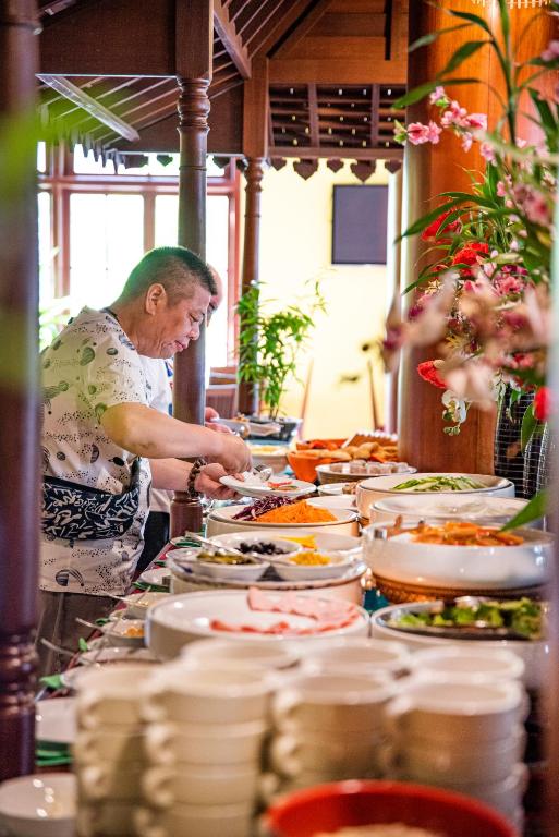 a man preparing food in a buffet line of dishes at Royal Crown Hotel & Spa in Siem Reap