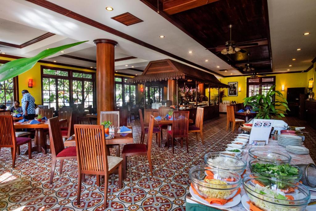 a dining room with tables and chairs with food at Royal Crown Hotel & Spa in Siem Reap