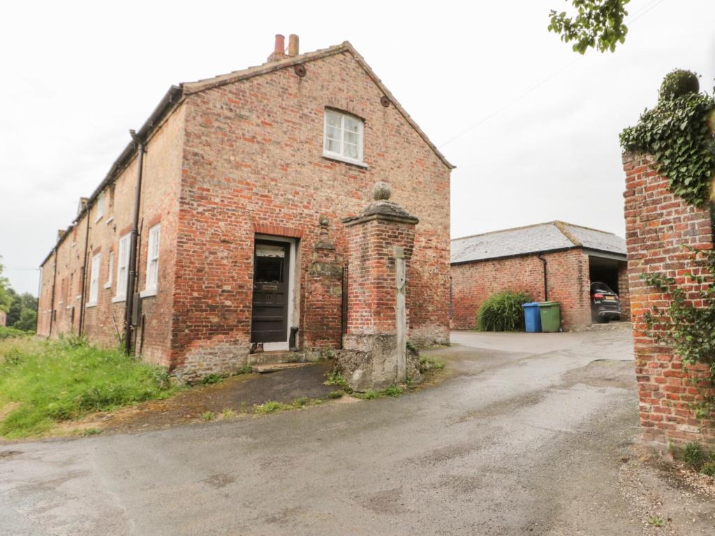 an old brick building with a door on a street at Bella's Cottage in Great Driffield