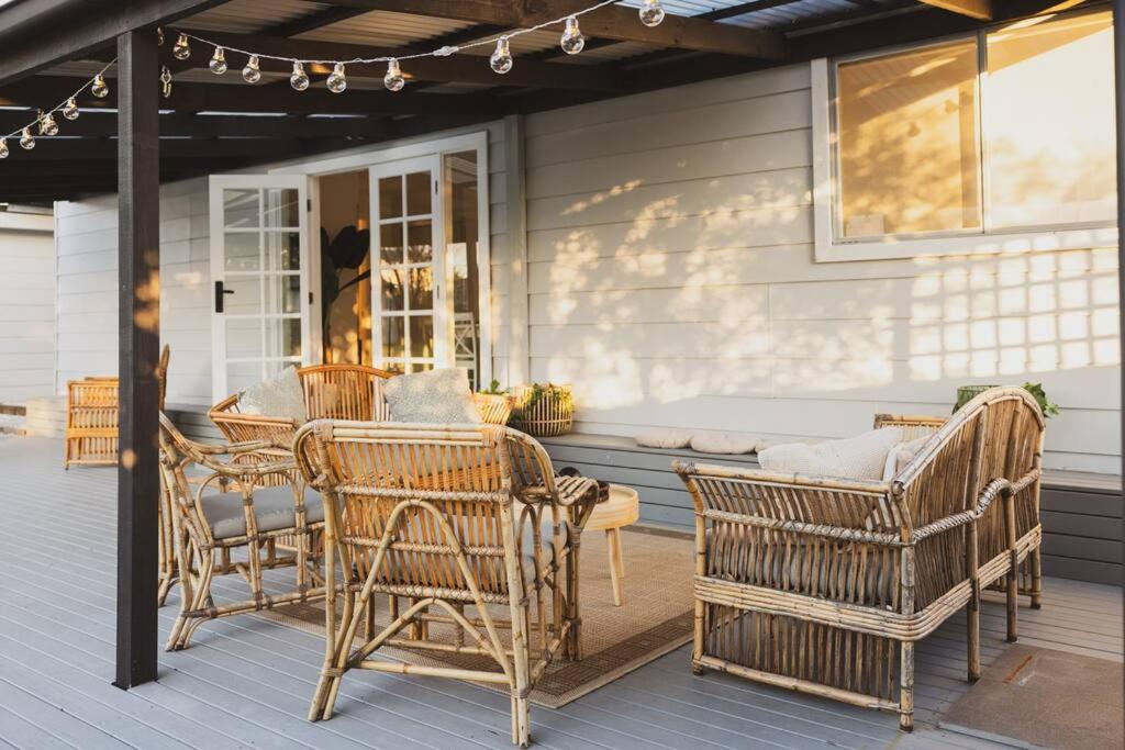 een patio met rieten stoelen en een tafel op een veranda bij Halcyon Days the perfect getaway, pet friendly! in Cessnock
