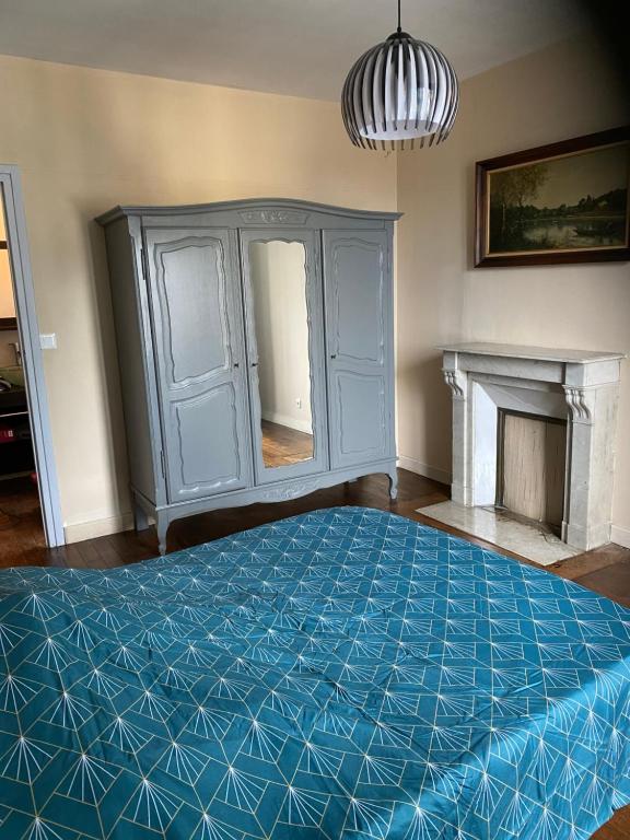 Maison centre ville في فير: غرفة نوم بسرير ازرق ومدفأة