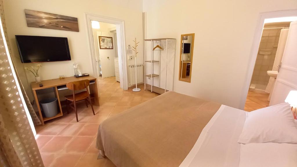 een slaapkamer met een bed, een bureau en een televisie bij BED&BOOK Palazzo Cutelli in Palermo