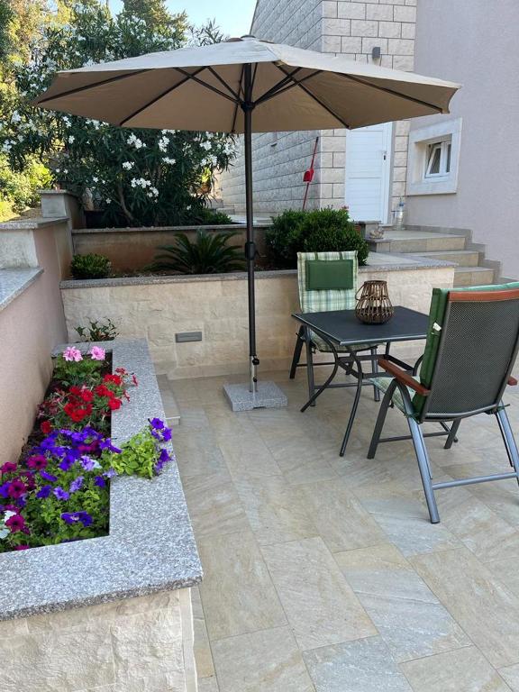 a patio with a table and an umbrella and flowers at MARILU in Korčula