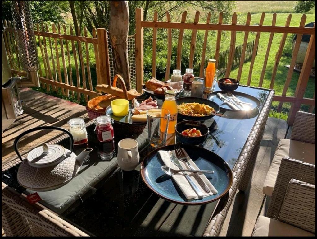 - une table avec des assiettes de nourriture sur une terrasse dans l'établissement La Cabane d'Ode, à Sainte-Ode