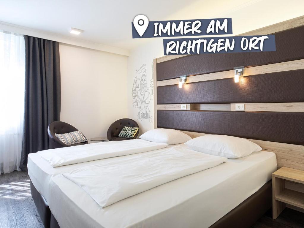ACHAT Hotel Kaiserhof Landshut في لاندشوت: غرفة في الفندق بسريرين وعلامة