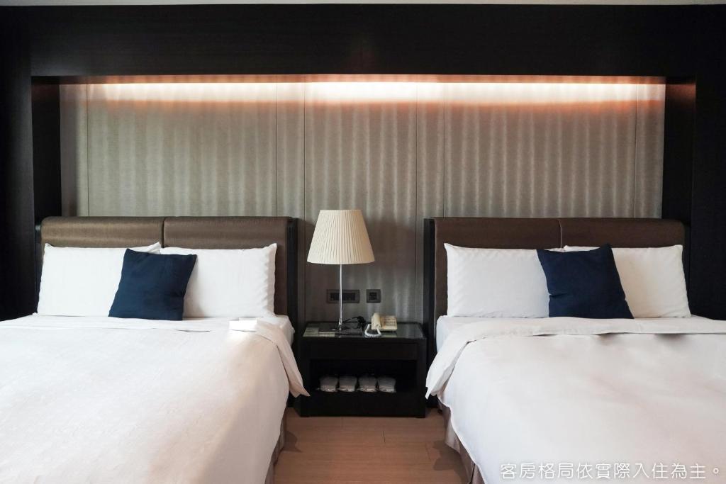 a bedroom with two beds with blue and white pillows at Talmud Hotel Kaohsiung LoveRiver in Kaohsiung