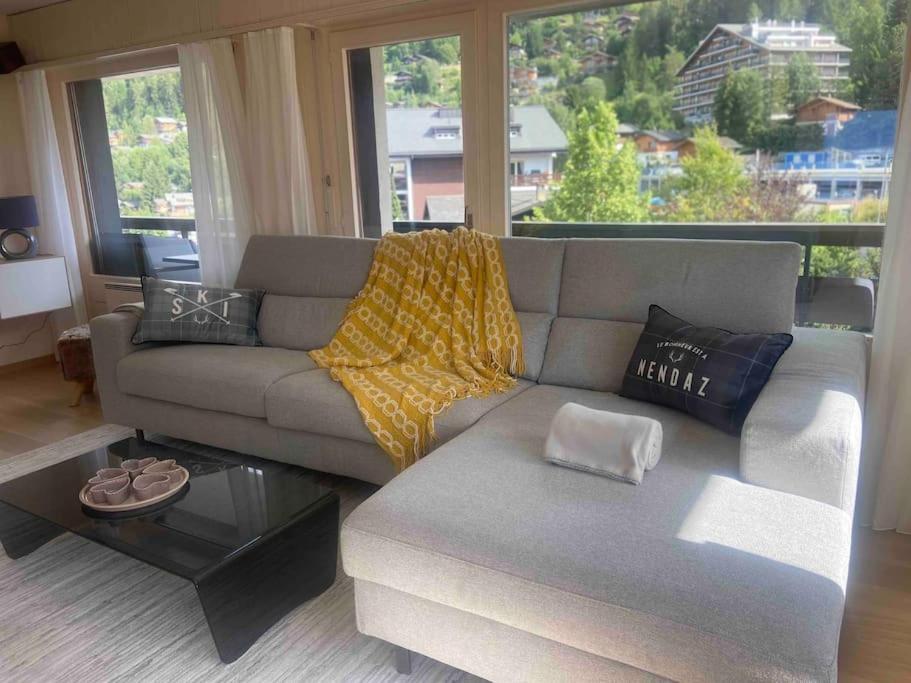 a living room with a couch and a large window at Sunny Swiss apartment 6P near Télécabine by Jolidi in Nendaz