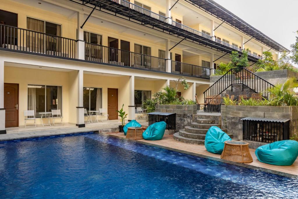 a hotel swimming pool with blue pillows in front of a building at Cove Kanaya in Seminyak