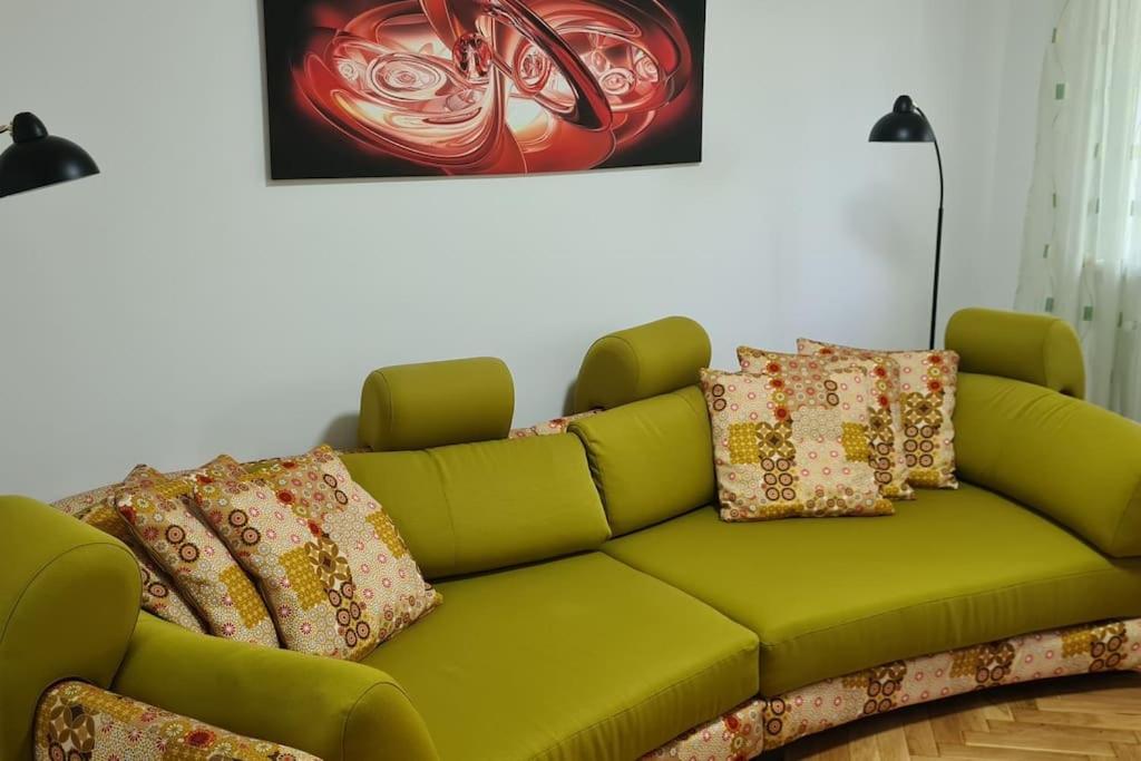 un sofá verde con almohadas en la sala de estar. en Apartament 3 camere, doua bai integral pentru familie sau grup, en Cugir