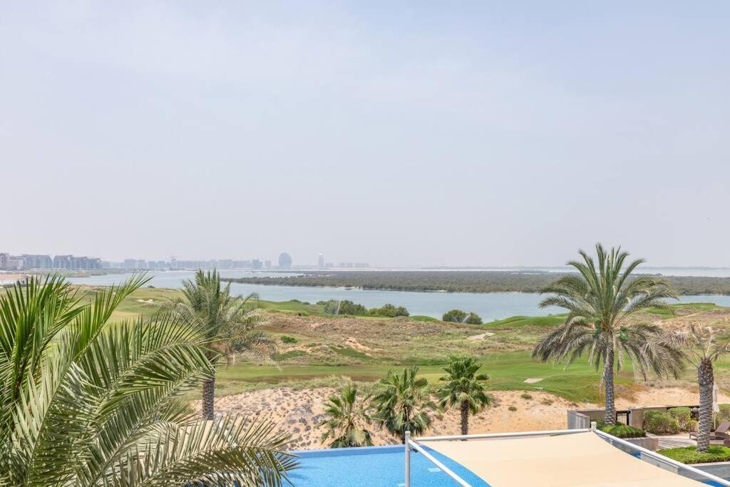 widok na pole golfowe z palmami i basenem w obiekcie Casa Noera, Yas Island 324 w Abu Zabi