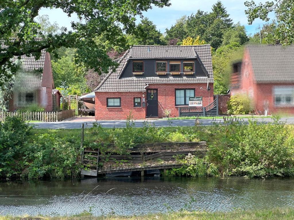 una casa in mattoni rossi con un ponte sul fiume di Ferienwohnung No 1am Golfplatz a Wiesmoor