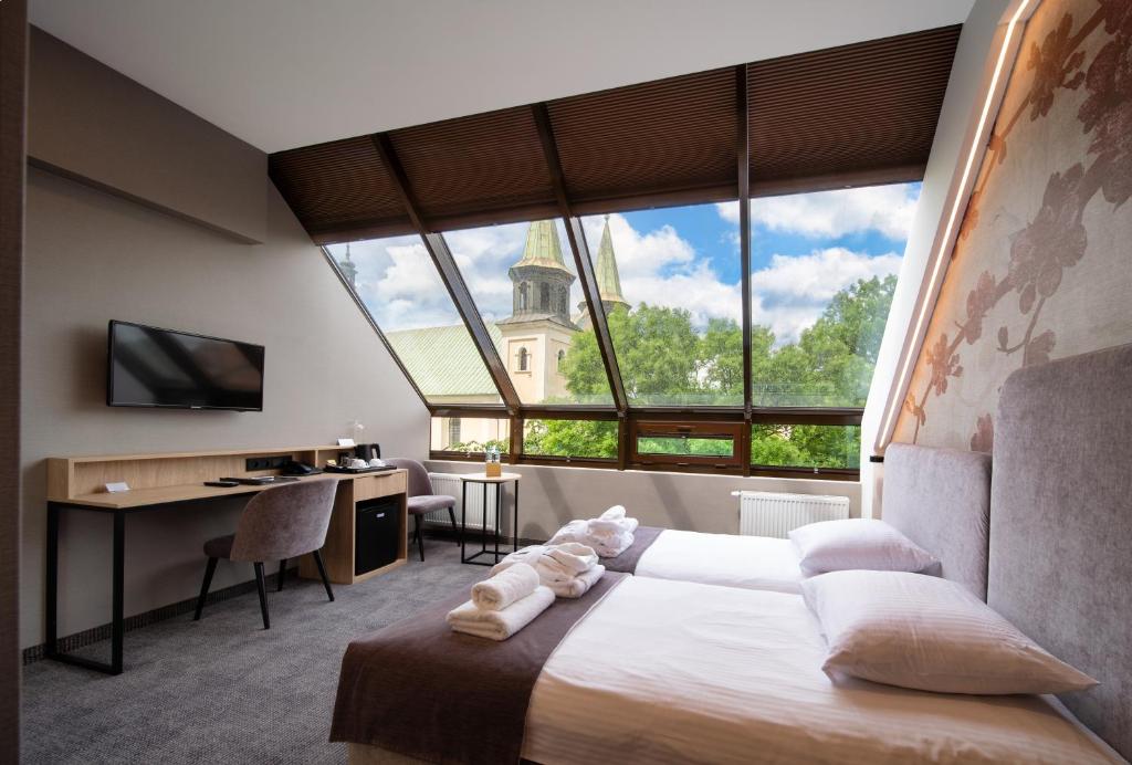a bedroom with a large window with a bed and a desk at Hotel Alexander in Krakow