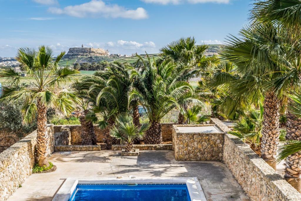 een villa met een zwembad en palmbomen bij Karmnu Holiday Farmhouse in Għasri