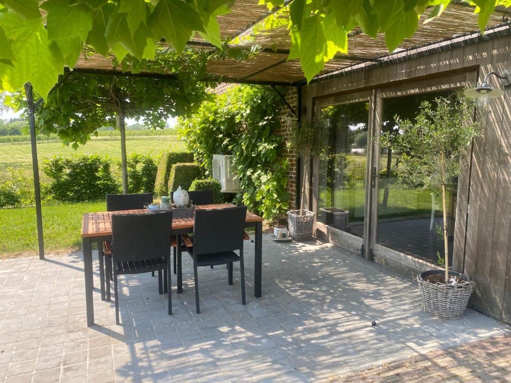 a patio with a table and chairs under a pergola at Gîte l' Ancien Four - De Bakoven in Lessines