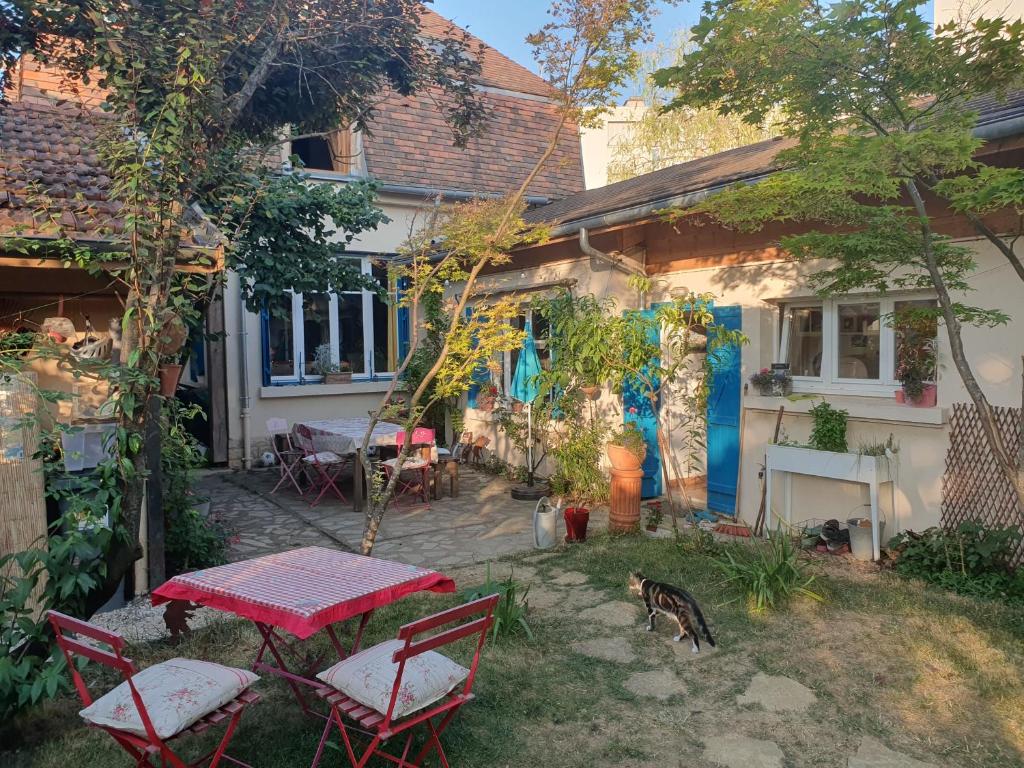 un patio con tavolo e sedie di fronte a una casa di Le Clos du Moulin Dijon,sa piscine, son jardin, au calme, la campagne à la ville a Digione