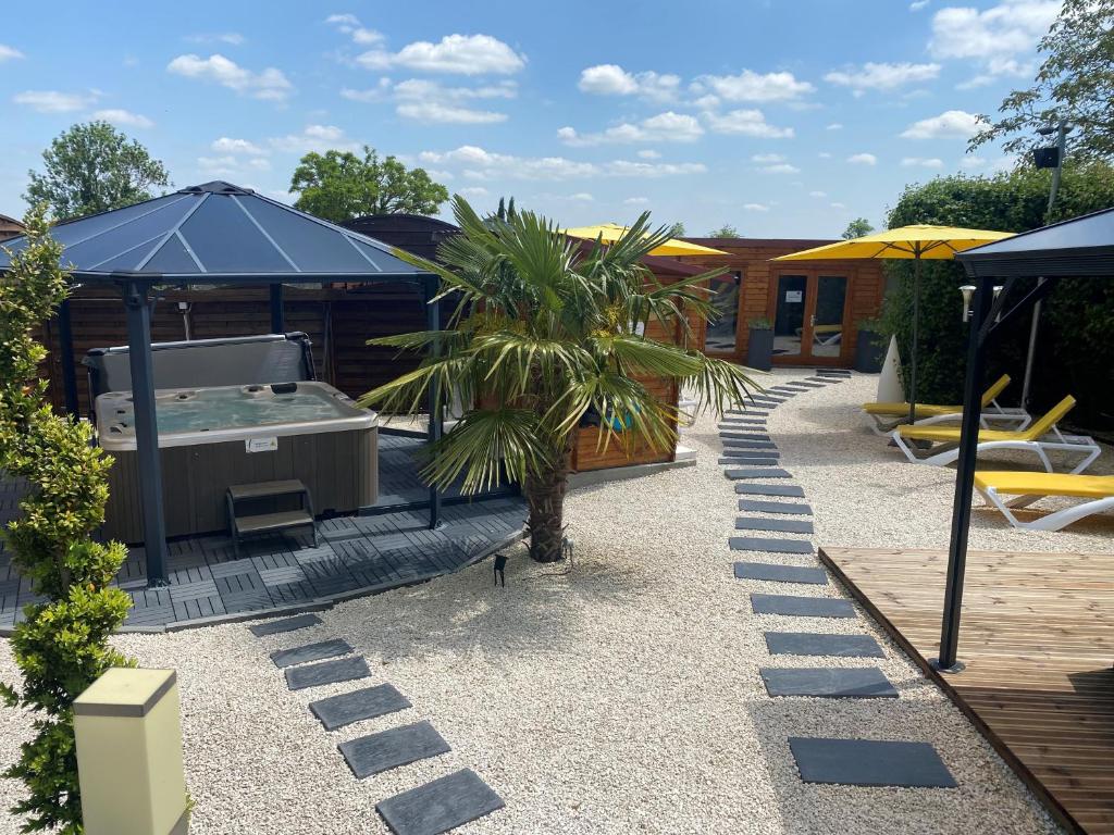 a backyard with a hot tub and a palm tree at Logis Hôtel Centrotel et Spa Bulles d'Allier in Montmarault
