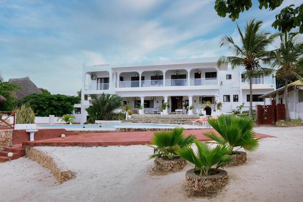 a large white building with palm trees in front of it at Met Beach Resort Malindi in Malindi