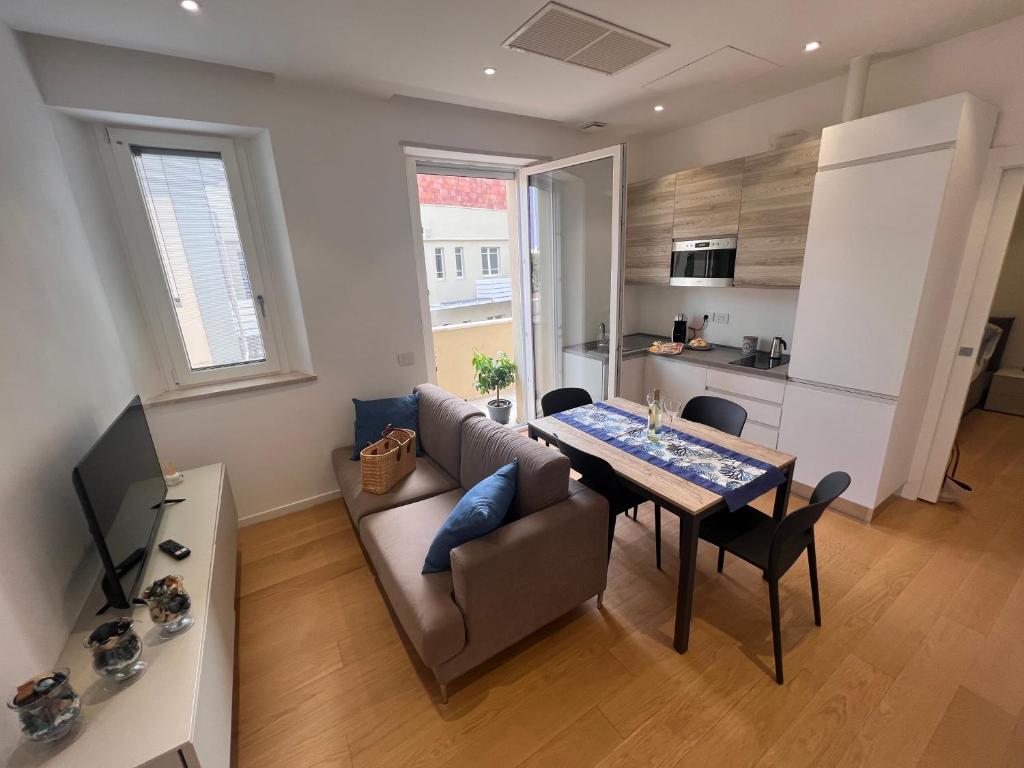 een woonkamer met een bank en een tafel en een keuken bij Happy Holiday Apartment in Cagliari