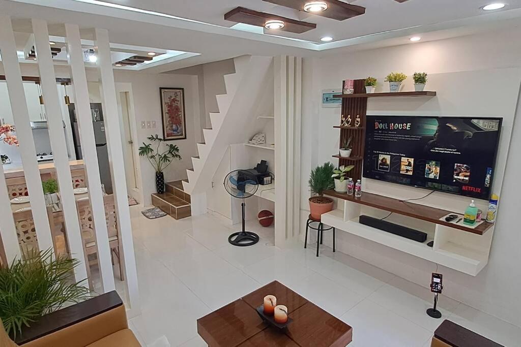 ein Wohnzimmer mit einem großen TV und einer Treppe in der Unterkunft Cozy Transient house in Calapan City. in Calapan