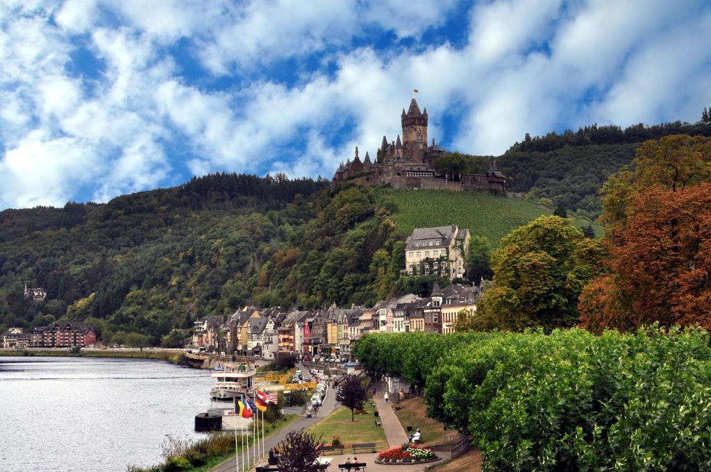 a castle on top of a hill next to a river at Moselstern Hotel Brixiade &Triton in Cochem