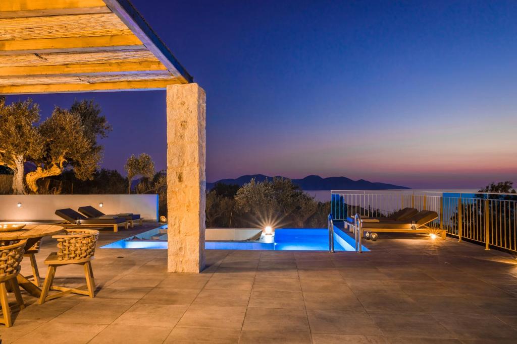 a patio with a table and chairs at night at Uberina - Olea Di Assos Villas in Asos